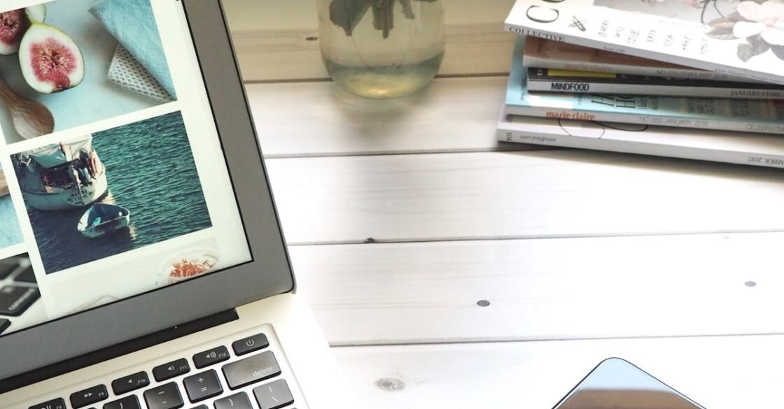 Elegant workspace featuring a laptop, smartphone, and fresh roses in a bright setting.